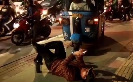 Seorang pria tiduran dan main HP untuk halangi bajaj lewat trotoar